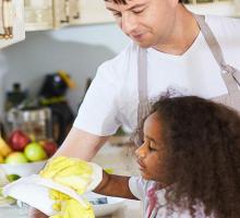 An adult and child washing dishes. 