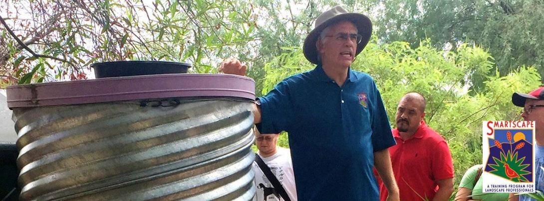 Man addressing a crowd next to a cistern. 