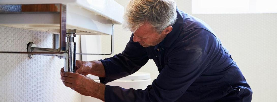 Man fixing a water drain for a sink
