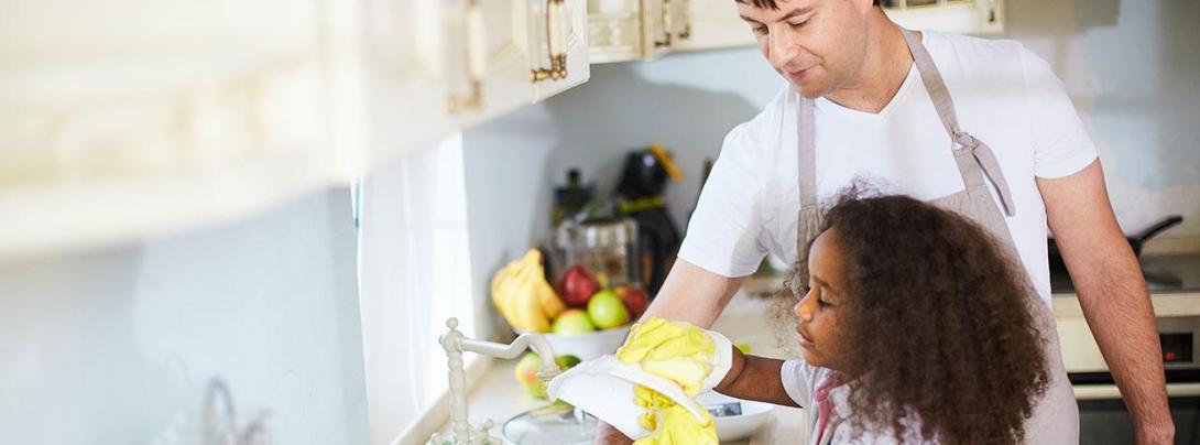 An adult and child washing dishes. 