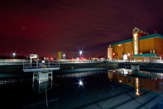 Phoenix Treatment Center at night, with the lights on and the city light illuminating the sky slightly red and purple. 